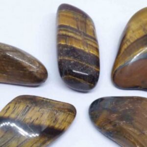 Cinq galets polis d'Œil de Tigre affichant une forte chatoyance avec des bandes dorées et brunes